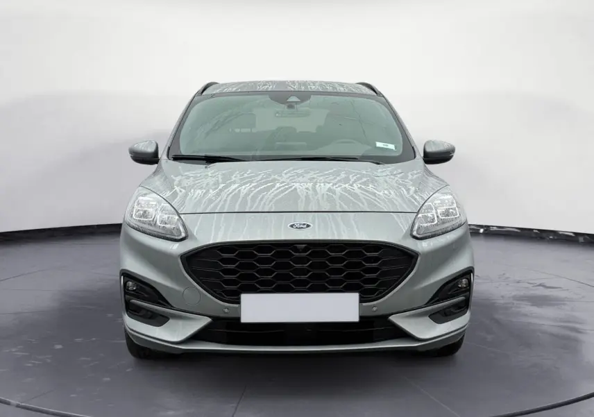 Vue frontale d'un Ford Kuga gris 2024 avec calandre noire et phares LED distinctifs, version hybride essence.