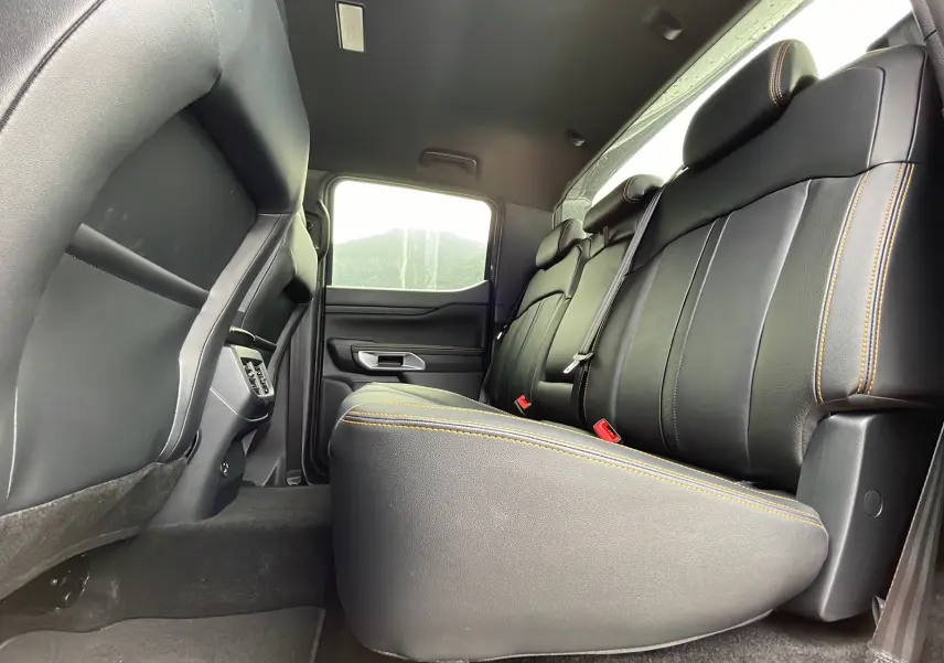 Vue intérieure côté arrière droit du Ford Ranger gris carbone 2026, sièges cuir noirs avec surpiqûres orange visibles.