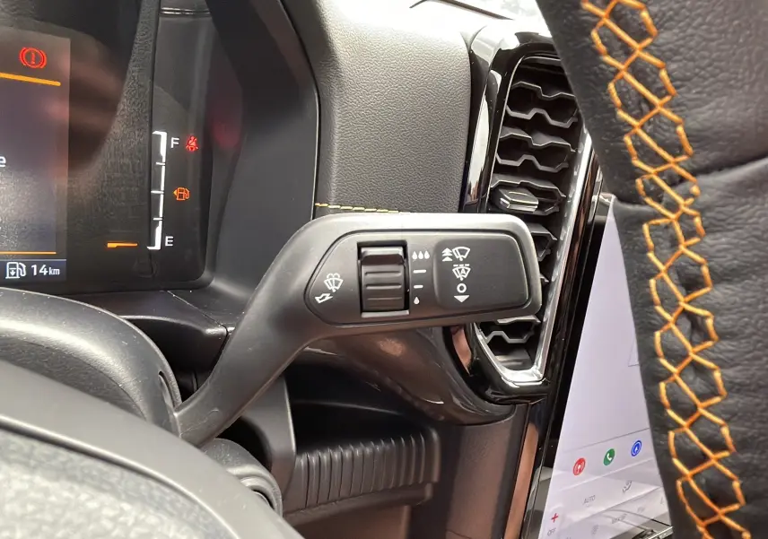 Gros plan sur la commande d'essuie-glace à gauche du volant cuir noir avec surpiqûres orange du Ford Ranger gris carbone 2026.