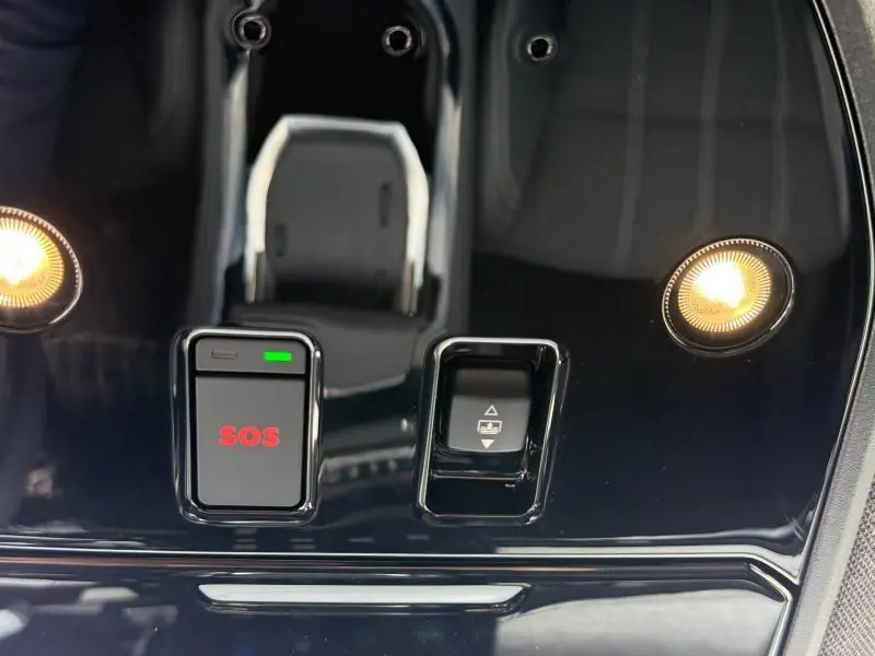 Gros plan sur la console centrale noire brillante du Renault Austral Rouge Flamme, avec bouton SOS et commande de toit ouvrant.