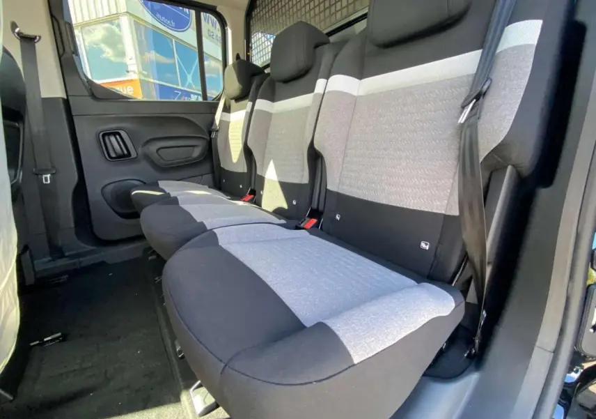 Vue intérieure côté droit des sièges arrière gris et noirs du Citroën Berlingo noir, avec grille de séparation visible.
