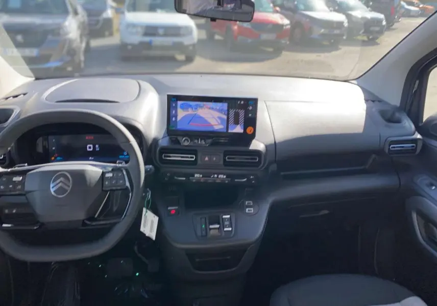 Vue intérieure avant du Citroën Berlingo noir 2026, tableau de bord avec écran caméra de recul et volant multifonction.
