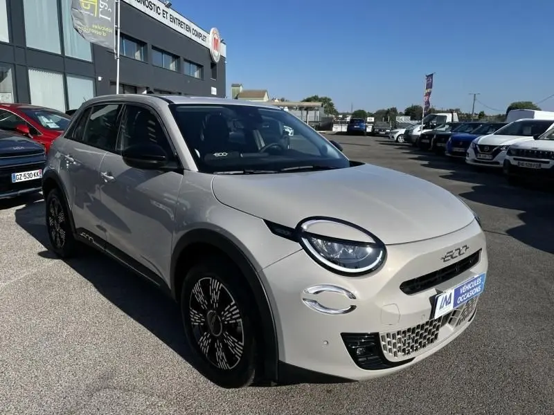 Vue 3/4 avant droite d'une FIAT 600 T-Gen 3 beige 2025 avec phares ronds et jantes noires stylisées.
