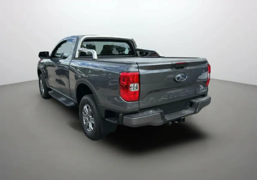 Ford Ranger gris carbone en 3/4 arrière droit avec arceaux inox et benne ouverte, vue sur hayon et feux rouges.