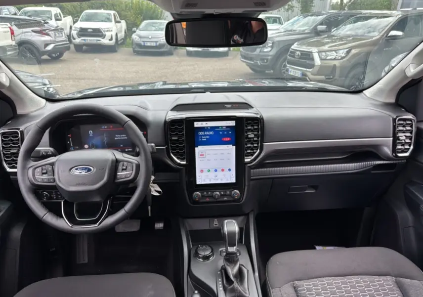 Intérieur du Ford Ranger gris carbone, vue frontale du tableau de bord avec écran tactile vertical et volant multifonctions.