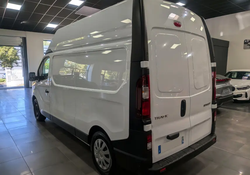 Vue 3/4 arrière gauche d'un Renault Trafic Fourgon blanc Glacier L2H2 en showroom avec hayon arrière fermé.