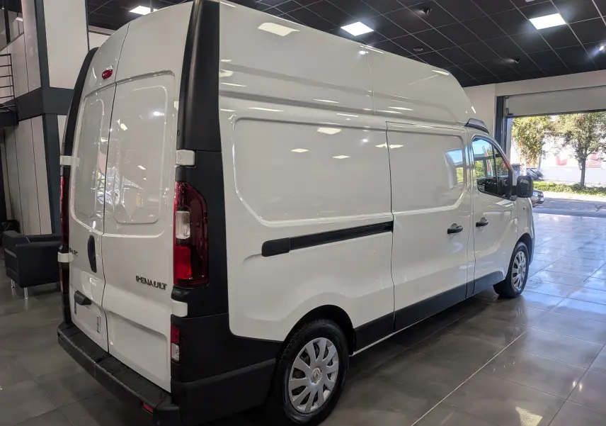 Renault Trafic Fourgon blanc glacier vu en 3/4 arrière droit dans un showroom lumineux avec toit haut L2H2.