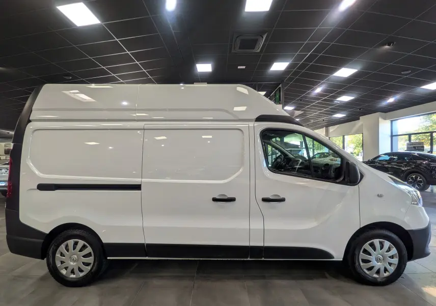Profil droit du Renault Trafic Fourgon L2H2 blanc glacier, vue en intérieur avec toit surélevé et jantes acier.