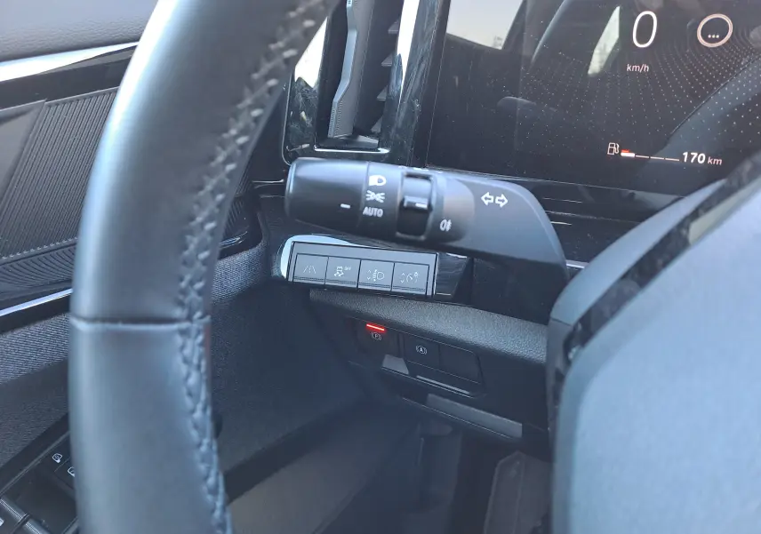 Gros plan sur la commande des phares et les boutons de sécurité à gauche du volant dans l’habitacle du Renault Austral gris schiste.