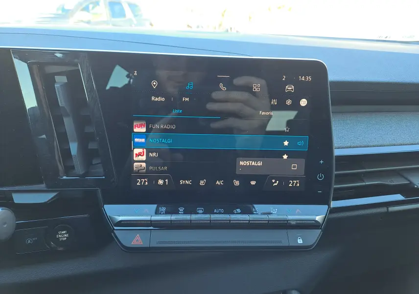 Vue intérieure centrée sur l'écran tactile multimédia du Renault Austral gris schiste avec commandes climatisation en dessous.