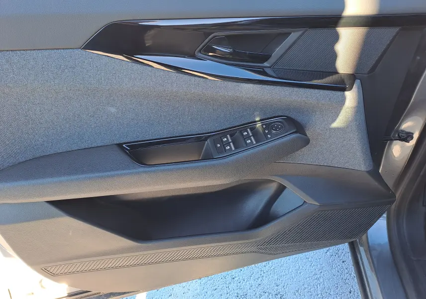 Vue intérieure côté gauche de la porte avant d'un Renault Austral gris schiste, avec commandes de vitres et garniture tissu.