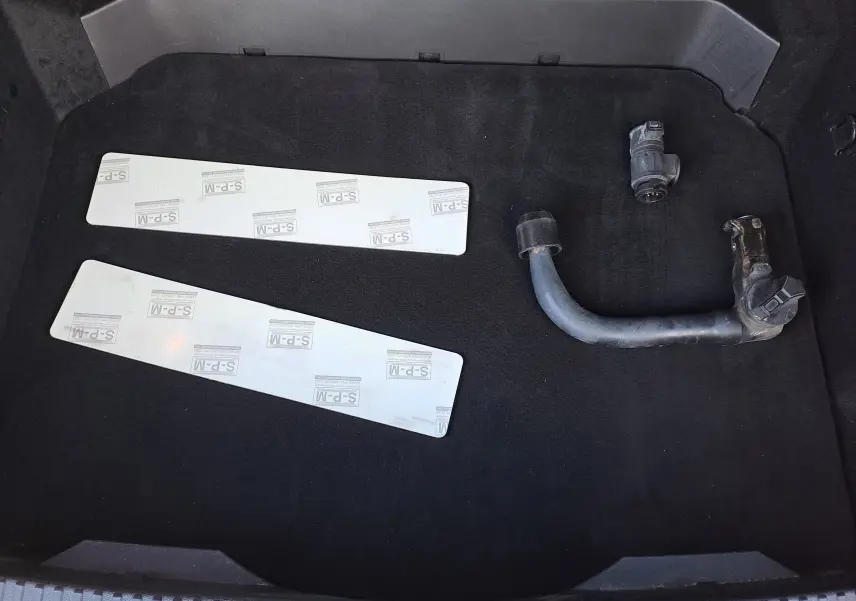 Vue du coffre d’un Renault Austral gris schiste 2023, montrant une barre d’attelage démontée et deux plaques blanches.