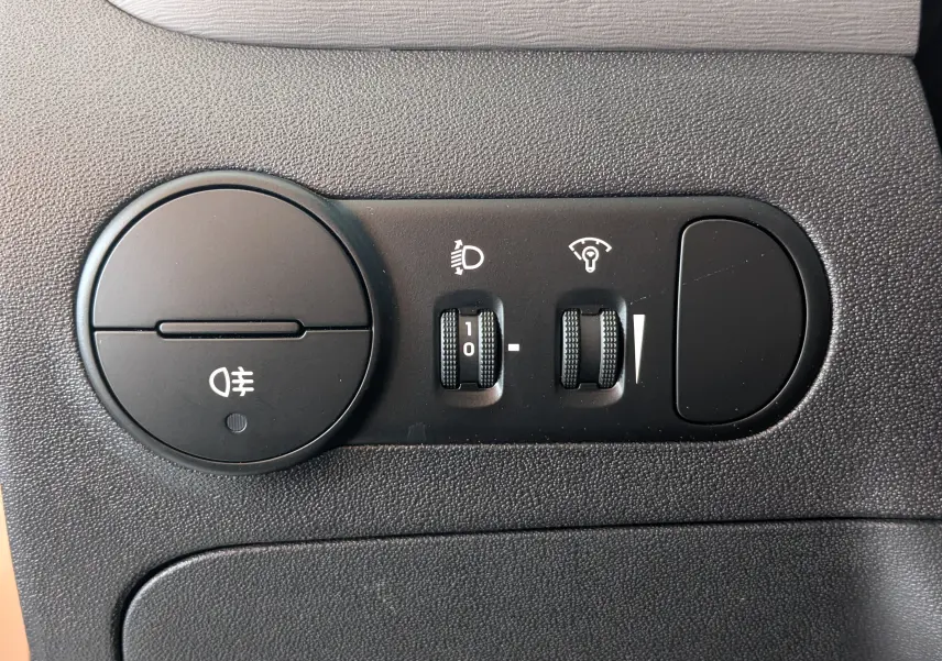 Gros plan sur les commandes d’éclairage et réglages du tableau de bord d’une Hyundai i10 gris clair de 2010.