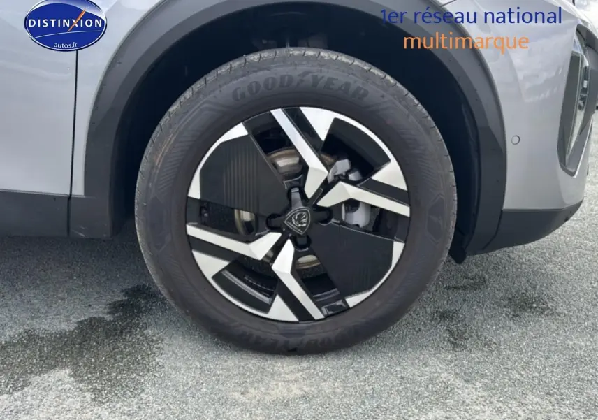 Gros plan sur la roue avant droite avec jante alu noire et argentée du Peugeot 2008 gris artense.