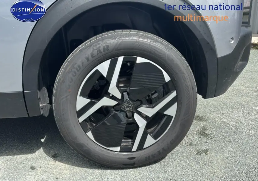Gros plan sur la roue avant droite du Peugeot 2008 1.2 100 allure gris artense avec jante alu bicolore.