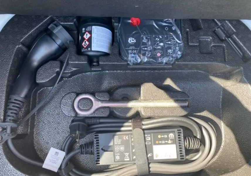 Gros plan sur le coffre avec le câble de recharge électrique et les outils de la FIAT 500 Action blanche 2022.
