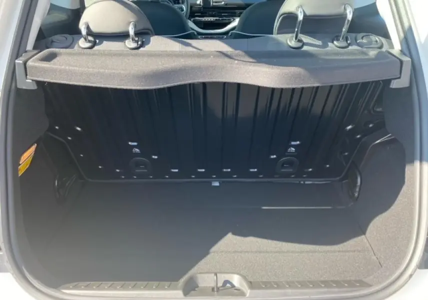 Vue du coffre ouvert d'une FIAT 500 électrique blanche, montrant l'espace de rangement et l'intérieur arrière du véhicule.