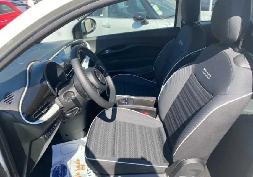 Vue intérieure côté conducteur de la Fiat 500 électrique blanche 2022, sièges noirs avec logo 500 brodé.