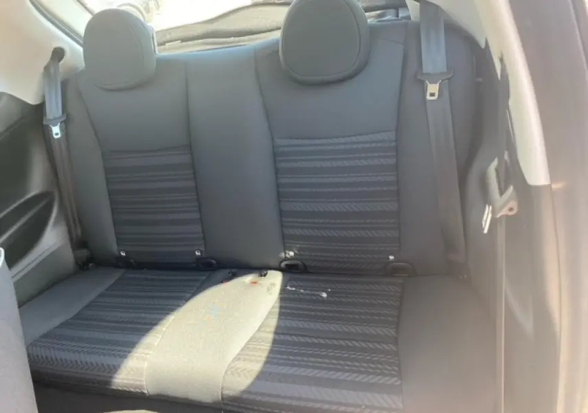 Vue intérieure sur la banquette arrière noire de la Fiat 500 électrique blanche, avec ceintures de sécurité visibles.