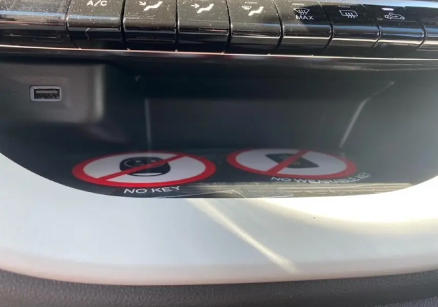Vue rapprochée de la console centrale blanche de la Fiat 500 électrique 2022 avec boutons de climatisation et port USB visible.