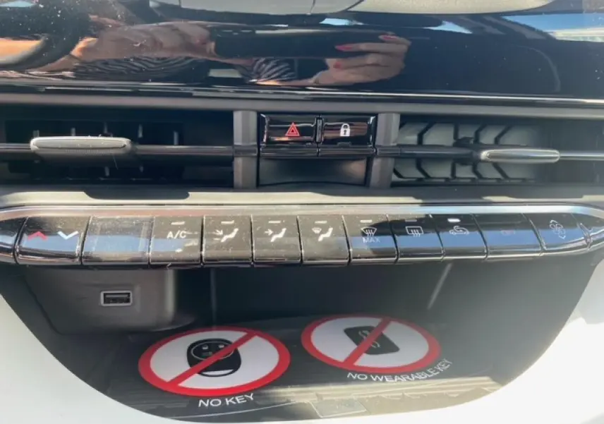 Vue rapprochée de la console centrale noire du Fiat 500 électrique blanc, avec commandes climatisation et ventilation.