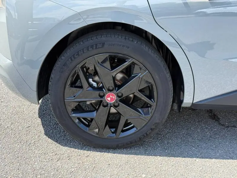 Gros plan sur la roue arrière droite d'une DS4 2024 gris Platinium avec jante alliage noire au design géométrique.