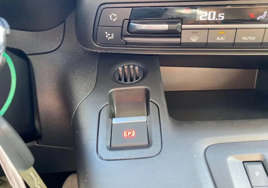 Détail intérieur du frein de stationnement électrique et commandes de climatisation du Citroën Berlingo noir 2026.