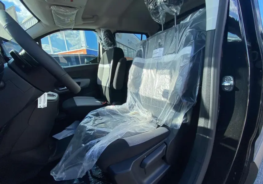 Vue intérieure côté conducteur du Citroën Berlingo noir 2026, siège avant protégé par une housse plastique.