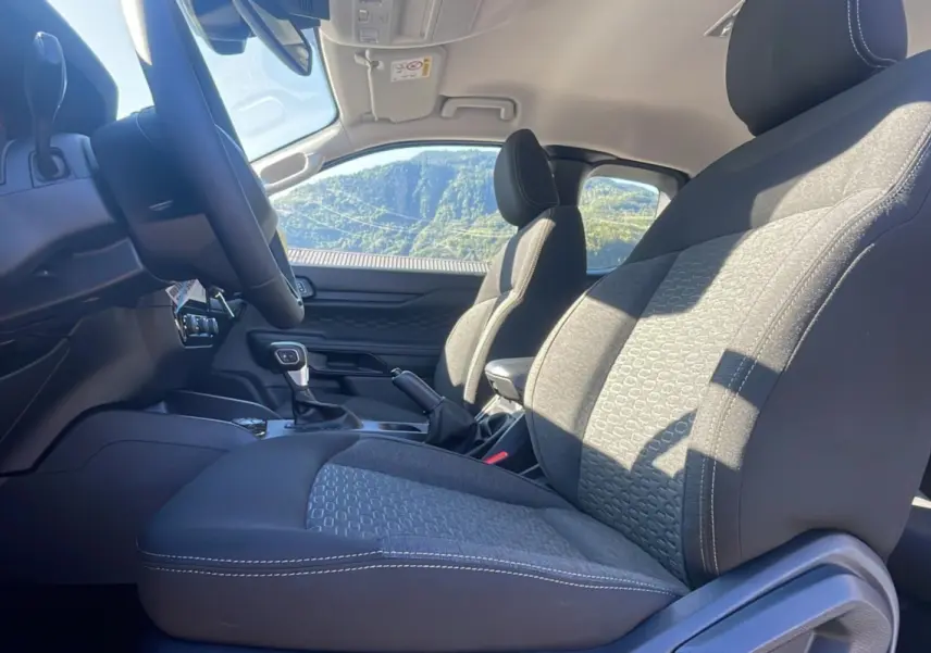 Vue intérieure côté conducteur du Ford Ranger 2026, sièges tissu gris avec surpiqûres blanches et volant multifonctions.