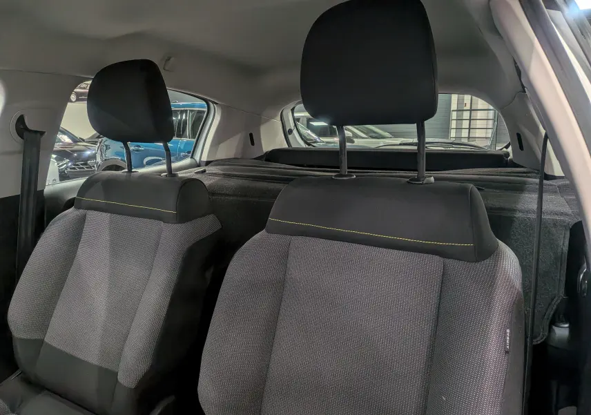Vue intérieure montrant les sièges avant en tissu gris et noir avec surpiqûres jaunes d'une Citroën C3 Société blanc banquise.