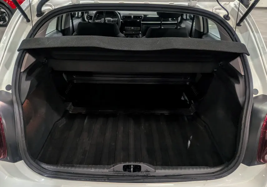 Coffre ouvert vu de l'arrière d'une Citroën C3 Société Blanc Banquise, montrant l'espace de chargement vide et la plage arrière relevée.