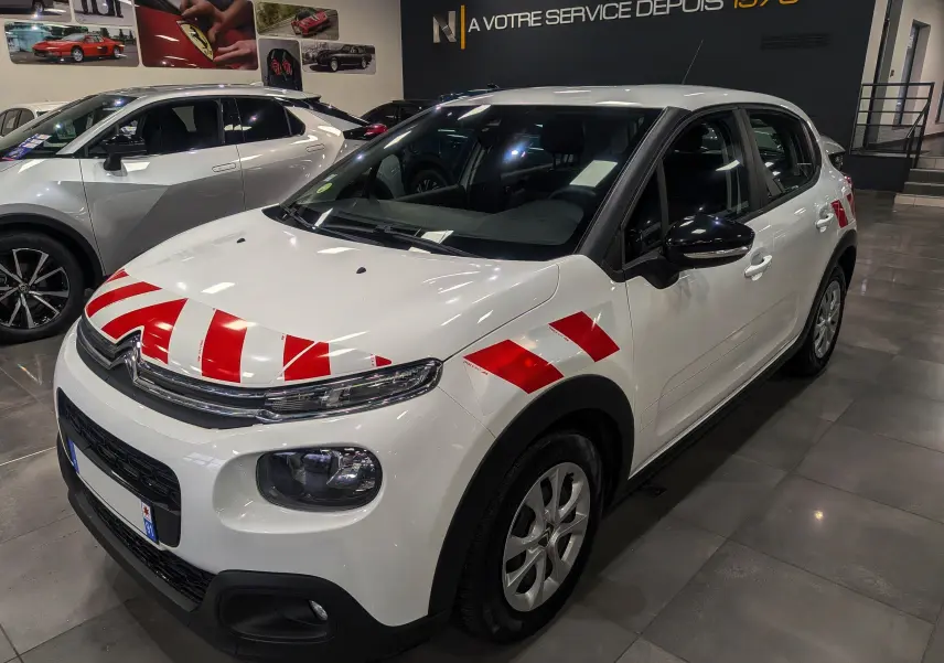 Citroën C3 Société blanc banquise vue 3/4 avant droit avec bandes rouges de signalisation sur capot et ailes.