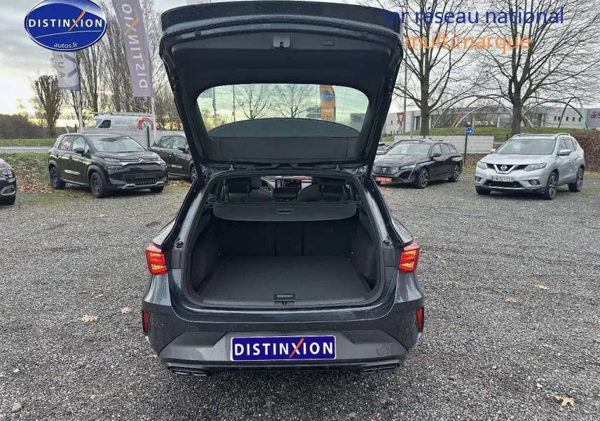 Vue arrière d'une CUPRA LEON ST gris magnétique avec coffre ouvert sur parking extérieur.