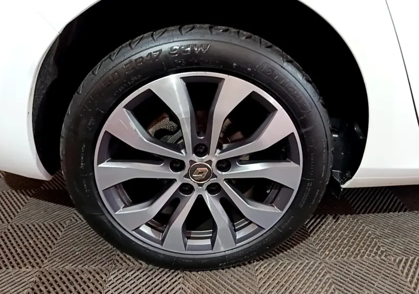 Gros plan sur la roue avant droite de la Renault Mégane blanche 2023 avec jante alliage gris et logo Renault central.