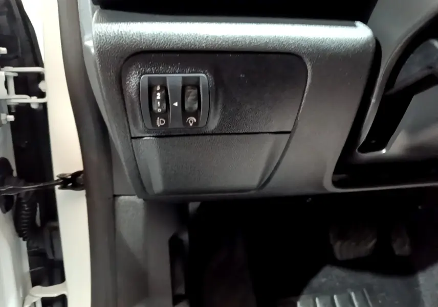 Détail des commandes d’éclairage et réglage sonore côté gauche sous le tableau de bord d’une Renault Mégane blanche.