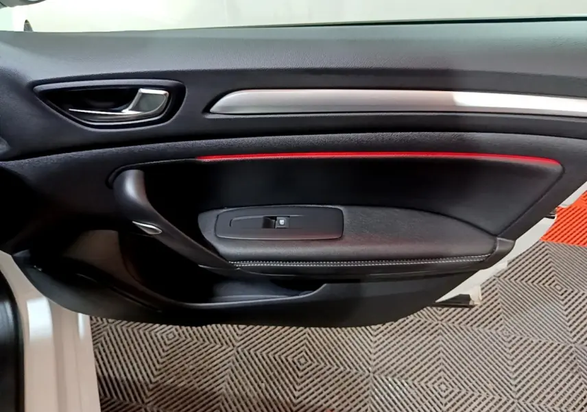 Vue rapprochée de la porte intérieure côté gauche noire avec bande lumineuse rouge de la Renault Mégane Techno 2023 blanche.