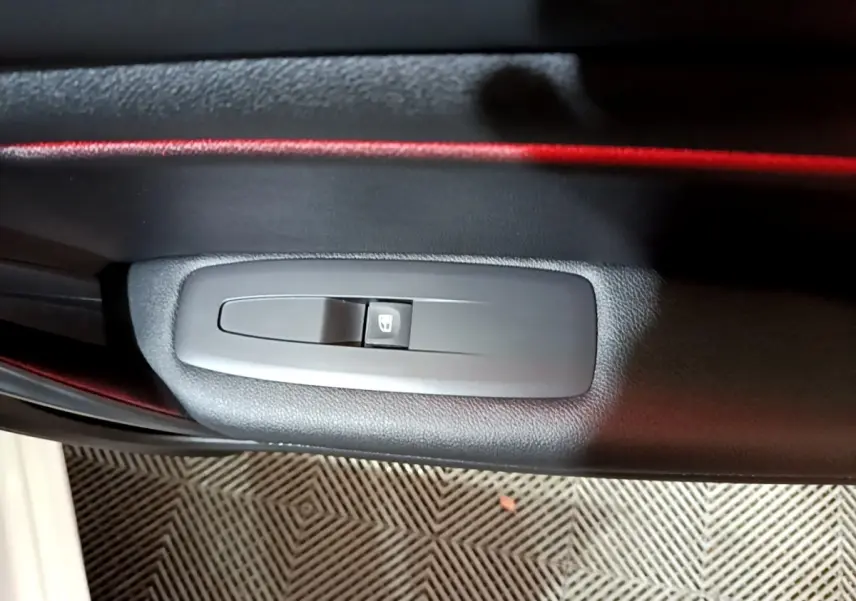 Détail du bouton de commande de lève-vitre sur la porte intérieure côté conducteur de la Renault Mégane blanche 2023.