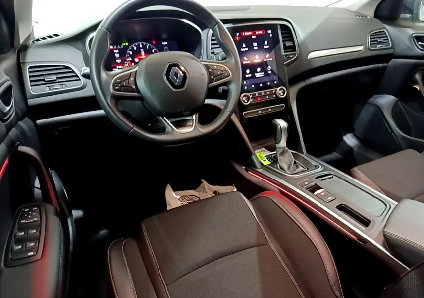 Vue intérieure avant droite de la Renault Mégane Techno TCe 140 2023, tableau de bord noir avec écran tactile vertical et éclairage d'ambiance rouge.