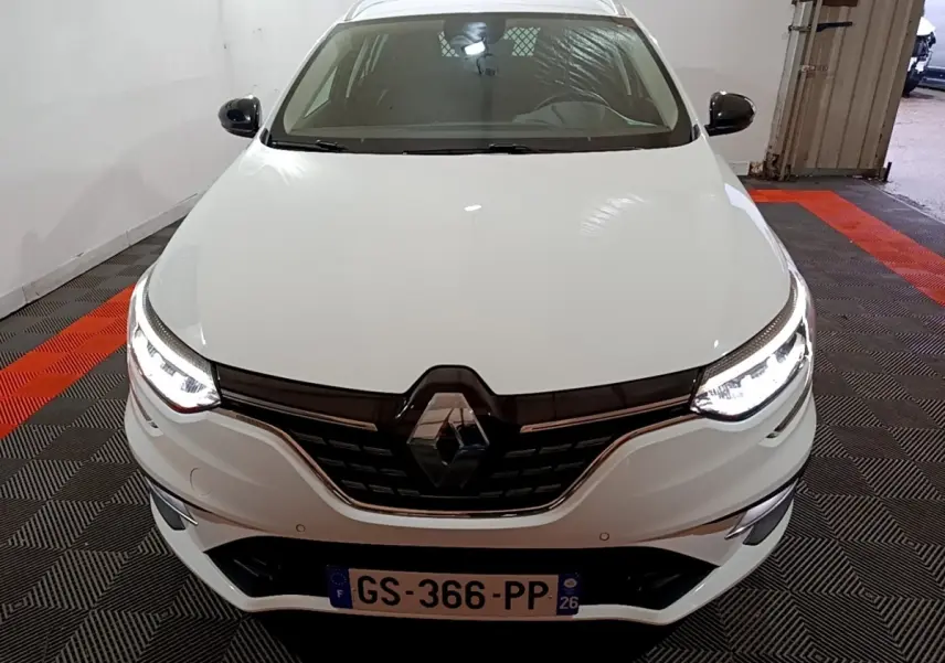 Vue avant d'une Renault Mégane Techno TCe 140 blanche avec phares LED allumés dans un garage.