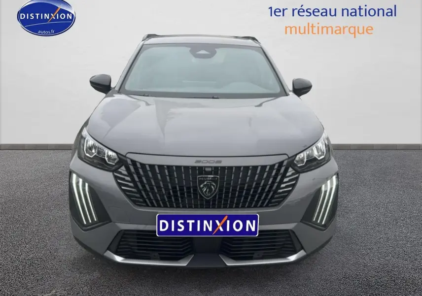 Vue frontale d'un Peugeot 2008 gris sélénite avec calandre noire et feux LED verticaux allumés.