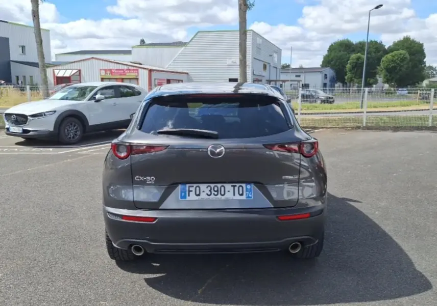 Vue arrière d'un Mazda CX-30 gris 2020 avec vitres surteintées et double sortie d'échappement visible.
