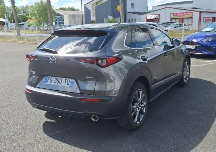 Vue 3/4 arrière droite d'un Mazda CX-30 gris 2020 avec vitres surteintées et jantes aluminium.