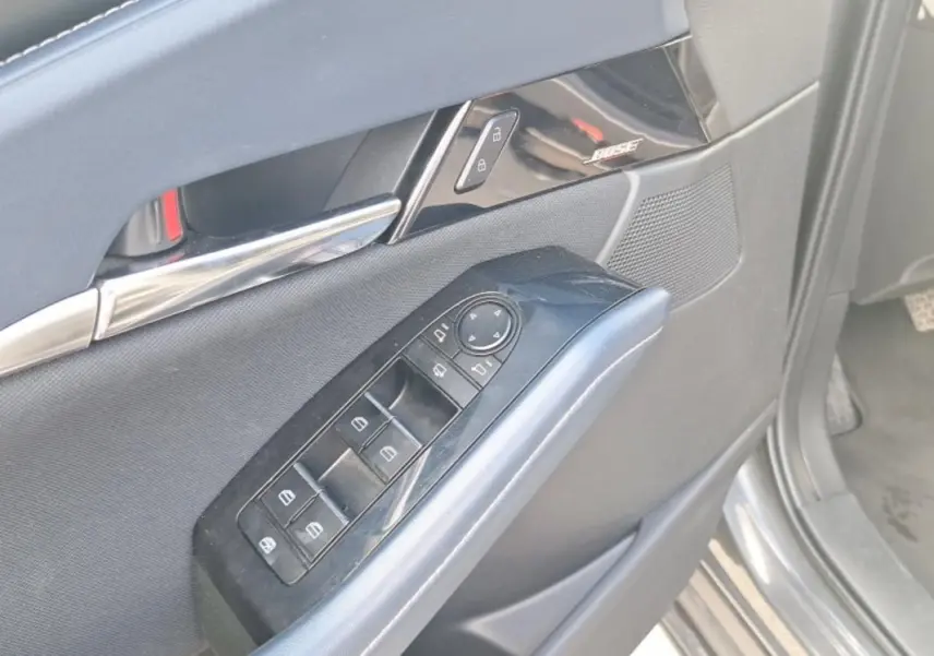 Gros plan sur la porte côté conducteur de la Mazda CX-30 gris, montrant les commandes des vitres et le haut-parleur Bose intégré.