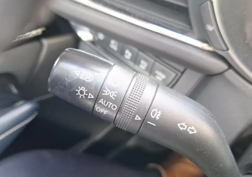 Gros plan sur la commande des feux et clignotants noire à l'intérieur du Mazda CX-30 gris, version 2020.