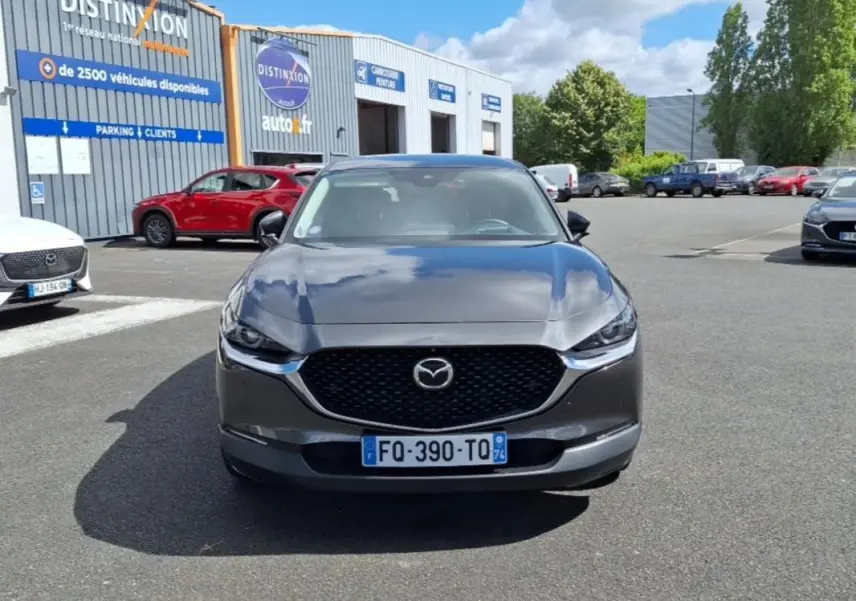 Vue de face d'un Mazda CX-30 gris 2020 avec calandre noire et phares effilés sur parking extérieur.