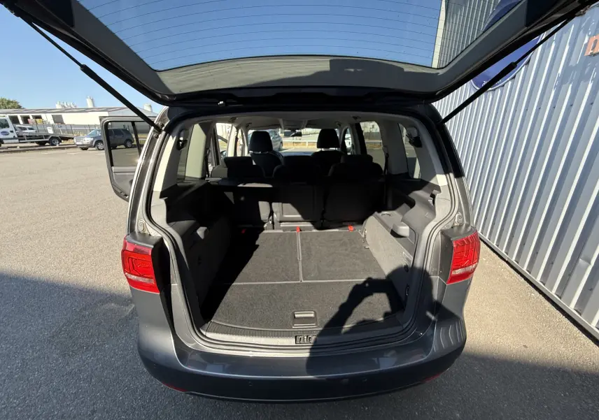 Vue arrière ouverte du Volkswagen Touran gris 2012, montrant le grand coffre et les sièges arrière rabattus.