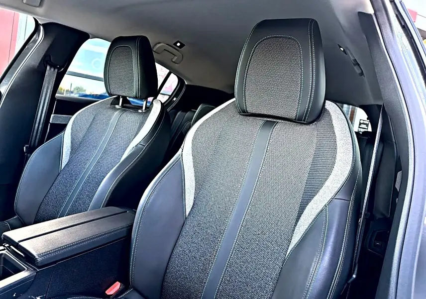 Vue intérieure rapprochée des sièges avant en tissu et cuir noir avec surpiqûres contrastantes dans une Peugeot 308 gris selenium.