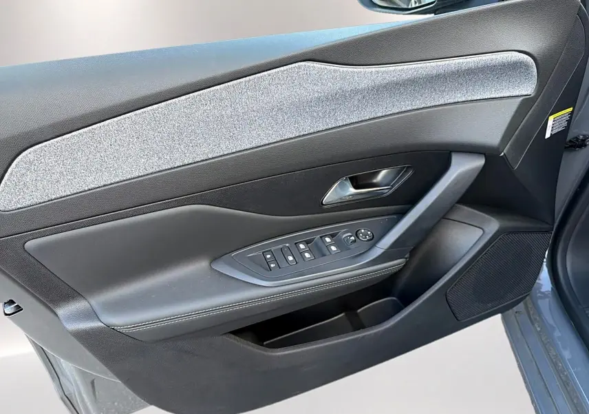 Vue rapprochée de la porte avant gauche gris selenium de la Peugeot 308 avec commandes de vitres et haut-parleur intégré.