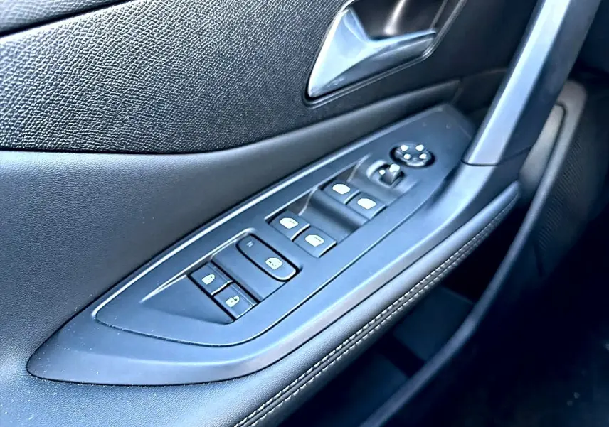 Gros plan sur la commande des vitres et rétroviseurs côté conducteur de la Peugeot 308 gris selenium, intérieur noir.