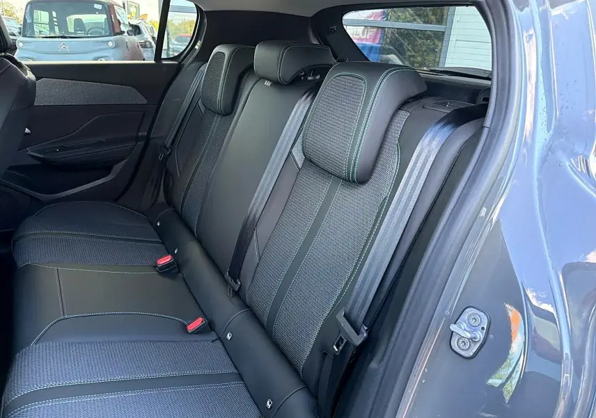 Vue intérieure sur la banquette arrière en tissu et cuir noir avec surpiqûres vertes d'une Peugeot 308 gris selenium.